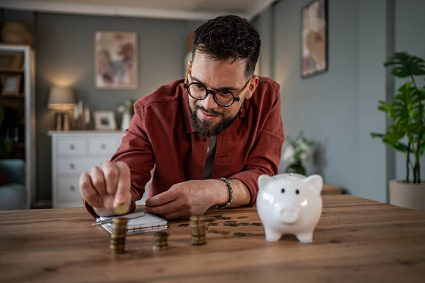 istock Man saving coins into piggy bank planning budget 2241209973