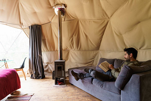 istock Man relaxing, reading in southern chile glamping dome 2241212027