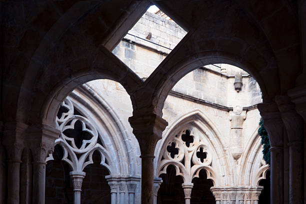Close-up view of weathered stone columns on a historic building facade, showcasing detailed texture and architectural elements. A quiet narrow street fades into the background