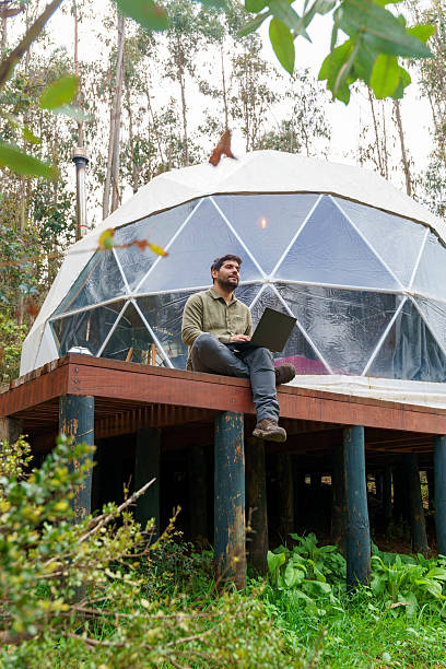 Man working remotely with laptop at glamping dome