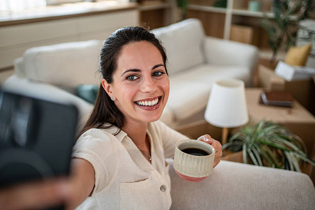 istock Woman drinking coffee taking selfie in new home 2241212987