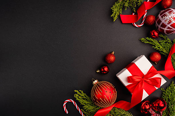 istock Christmas Gift with Red Ornaments and Greenery on Black 2241214525