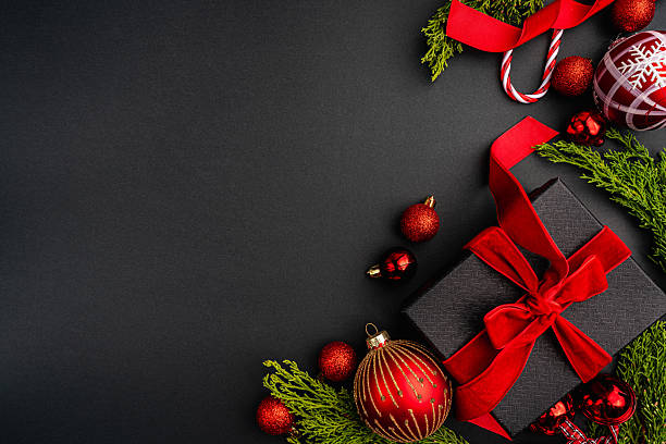 istock Christmas Gift with Red Ribbon and Ornaments on Black 2241214552