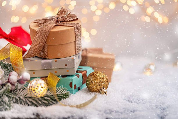 istock Stack of Festive Gift Boxes on Snow with Lights and Ornaments 2241214692