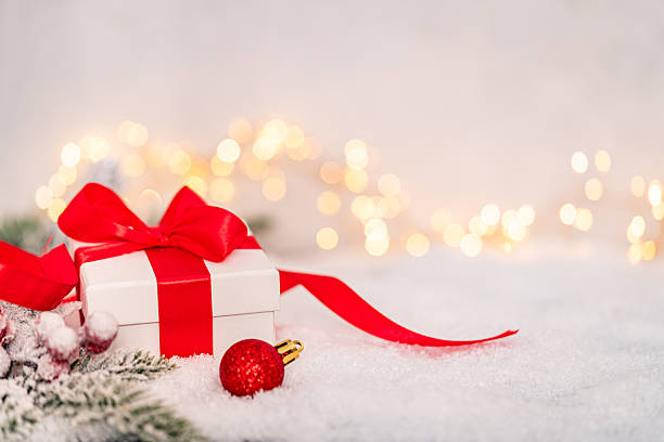 istock White Christmas Gift Box with Red Ribbon on Snowy Background 2241214720