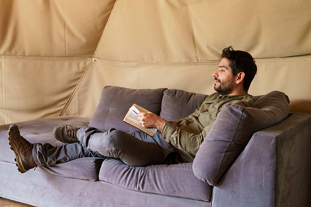 istock Man relaxing and reading book inside glamping dome tent 2241215054