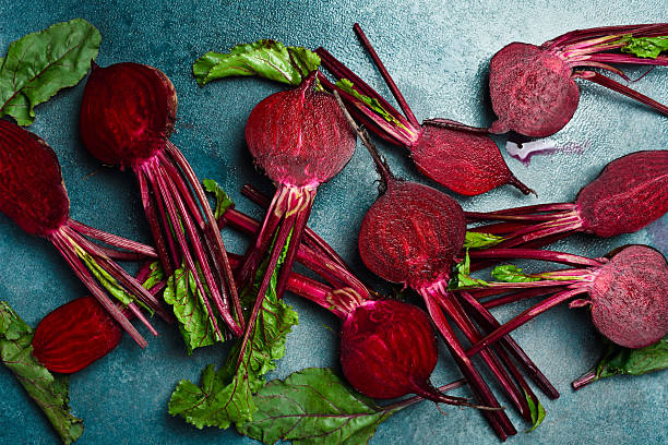 Background of fresh young beets with stems. Sliced beets on a stone background. Top view.