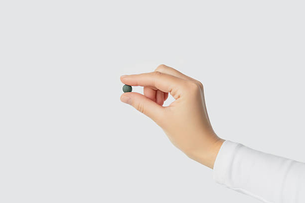 istock Hand holding a small green spirulina pill 2241216870