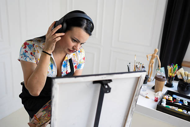Creative female painter painting on canvas with headphones on