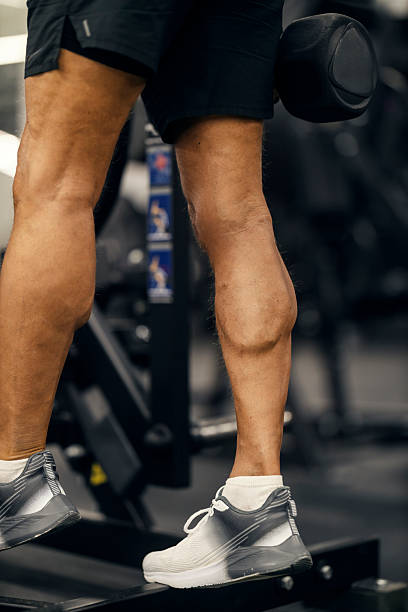 istock Man performing calf raise with dumbbell training legs in gym 2241230063