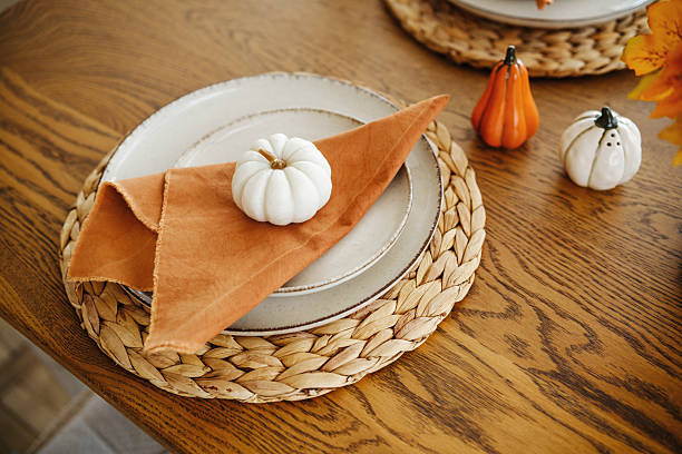 istock Autumn table setting with small pumpkins on plates, woven mats, and orange napkins. 2241230802