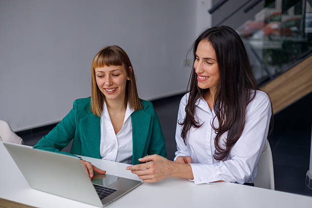 istock Businesswomen collaborating on laptop in modern office, working together on project, smiling and discussing 2241233268