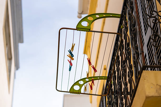 istock Clothespins in various colors hang from a drying rack attached to a wrought iron balcony railing. 2241235134
