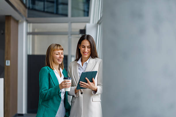 istock Businesswomen colleagues discussing new project on digital tablet during coffee break in modern office hallway 2241235233