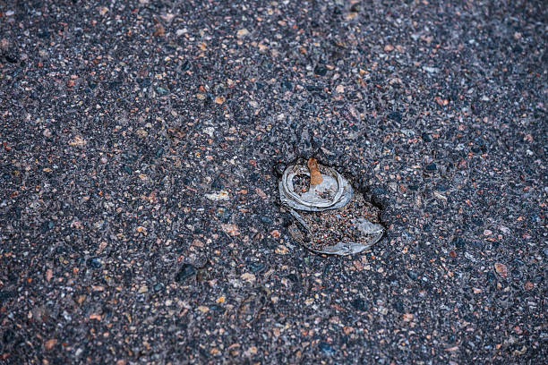 istock Flattened aluminum can embedded in asphalt street.. 2241235619
