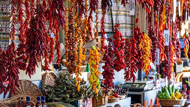Vibrant market scene with hanging chili peppers and fresh produce, showcasing a colorful and lively atmosphere.