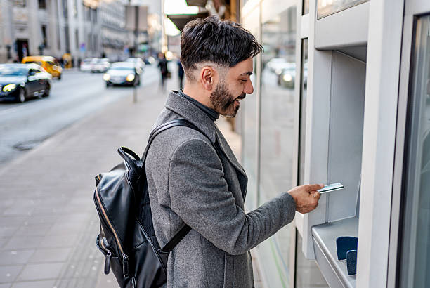 istock Man withdrawing money using credit card from atm in city 2241242730