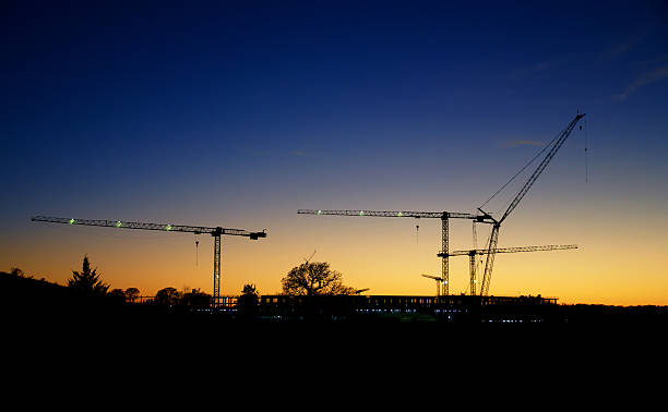 istock Construction cranes silhouettes against beautiful evening sunset 2241244330