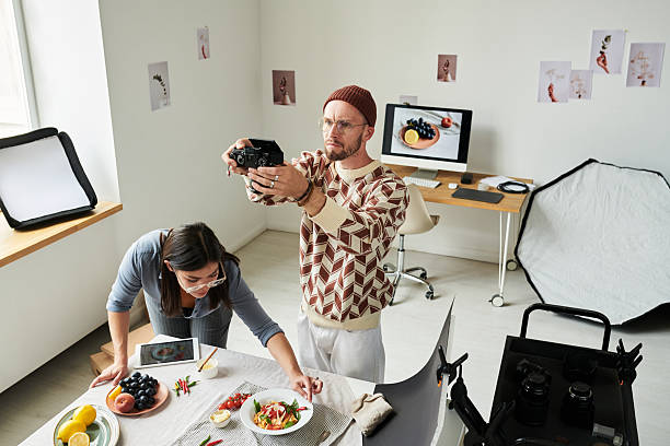 istock Man Photographing Food While Woman Arranging Table 2241245315