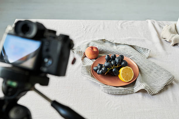 istock Digital Camera Photographing Fresh Grapes Lemon and Peach on Tablecloth 2241246234