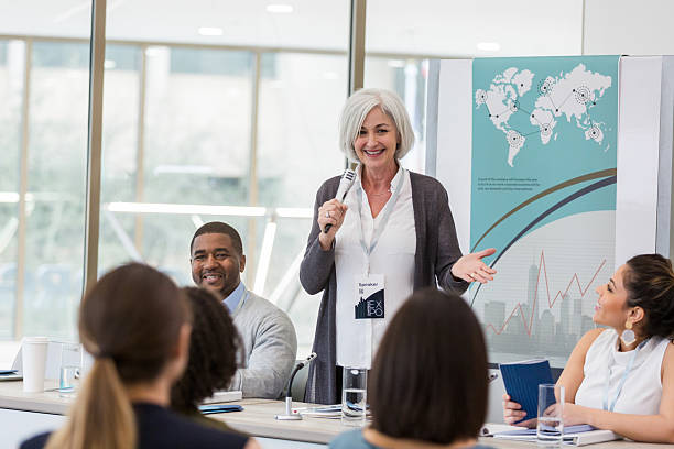istock Experienced female speaker engages diverse audience in a business presentation setting. 2241257215