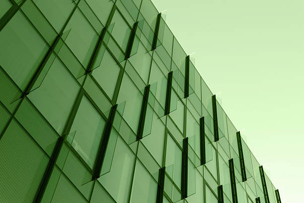 A striking image of a modern glass building facade in green tones, showing diagonal panels and repeating geometric patterns that convey architecture, scale, and contemporary design.