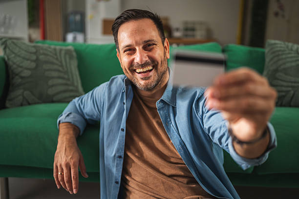 istock Smiling man holding credit card making online payment 2241259429