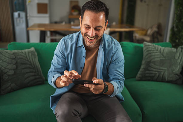 istock Man winning mobile game celebrating victory on couch 2241259477