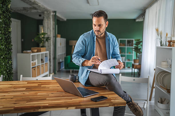 istock Man working remote from home office reviewing business documents 2241260398