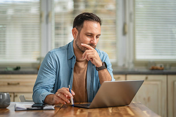 istock Man working from home, thinking, focusing on laptop 2241260769