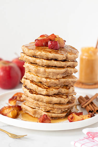 istock Stack of apple cinnamon pancakes with maple syrup on kitchen table with white background 2241260886