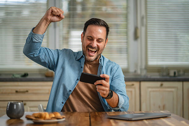 istock Man winning online game on smart phone celebrating success 2241260958