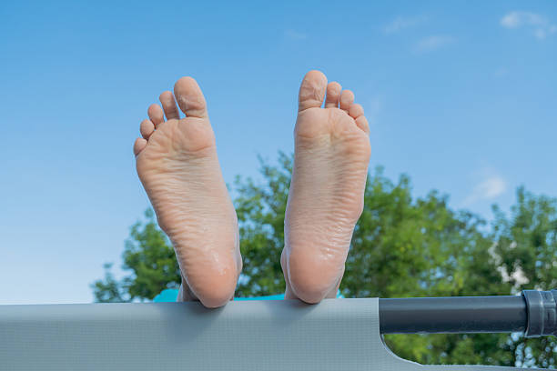 Bare feet relaxing on hammock under blue sky in summer.