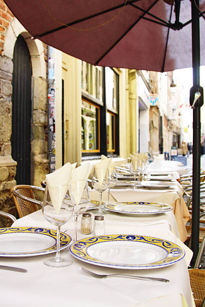 istock Outdoor dining setup featuring elegantly arranged tables with fine china, glassware, and napkins, shaded by a large umbrella, creating a charming atmosphere for al fresco dining experience 2241264969