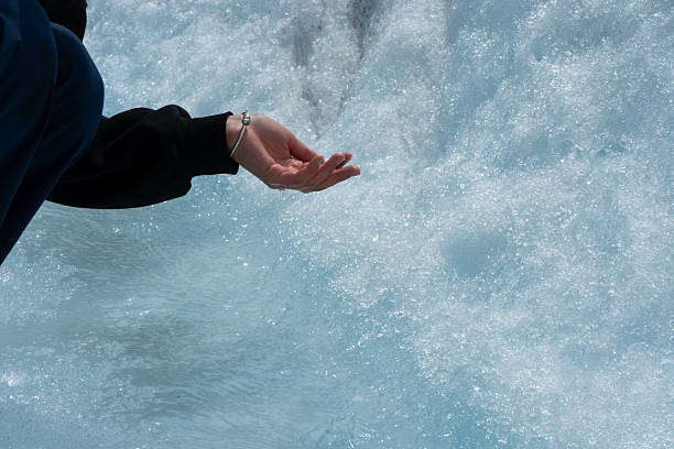 Female hand cupped catching fresh water from mountain lake