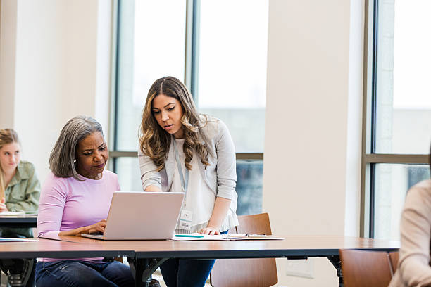istock Diverse group of women learning together on laptops in a bright indoor classroom. 2241269682