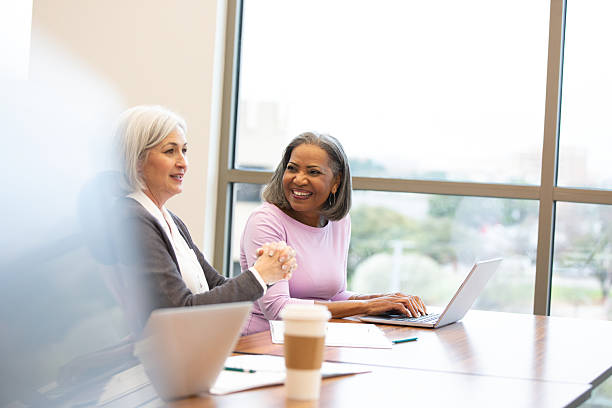 istock Two professional women of different ethnicities collaborating and smiling in a bright office setting. 2241269727