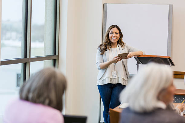 istock Confident instructor leads a presentation with a tablet in hand to an engaged audience. 2241269732