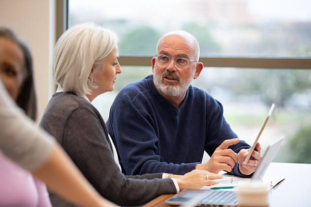 istock Three adults discussing something on a tablet and laptop indoors in office setting. 2241269747