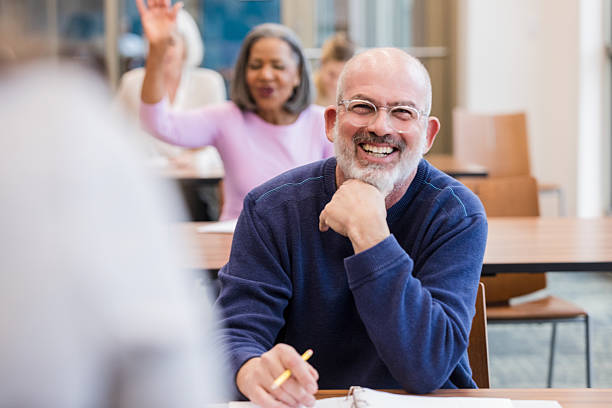 istock A man smiles and laughs while holding a pencil in a classroom setting, engaged in learning. 2241269790