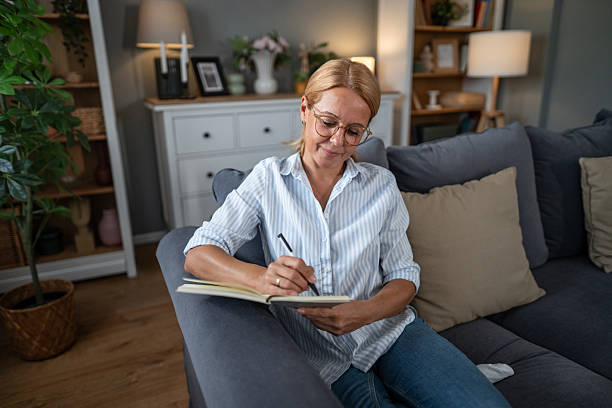 istock Woman relaxing on sofa writing in journal at home 2241272763