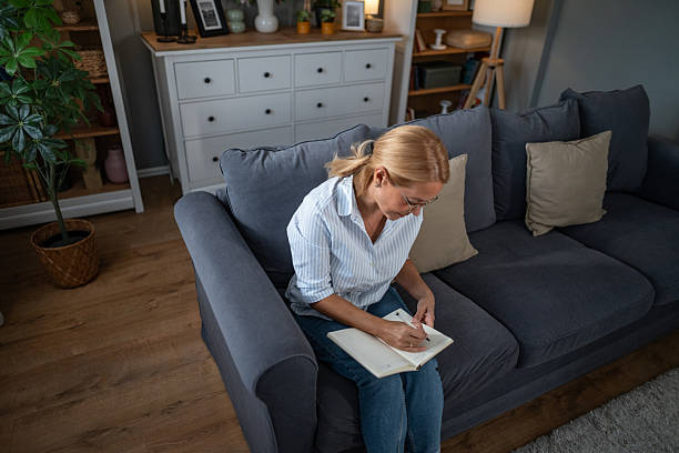Woman journaling on couch reflecting on thoughts