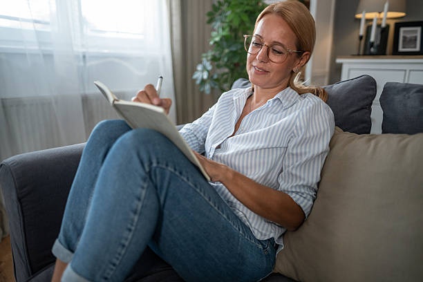 istock Woman journaling on sofa, writing in diary at home 2241272828