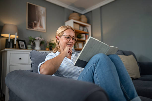 istock Woman enjoying reading book on sofa at home 2241272854