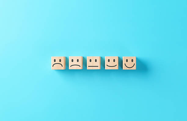 istock Customer satisfaction and feedback concept with wooden blocks displaying different emoji faces from sad to happy on blue background, representing user experience and review rating scale. 2241274657