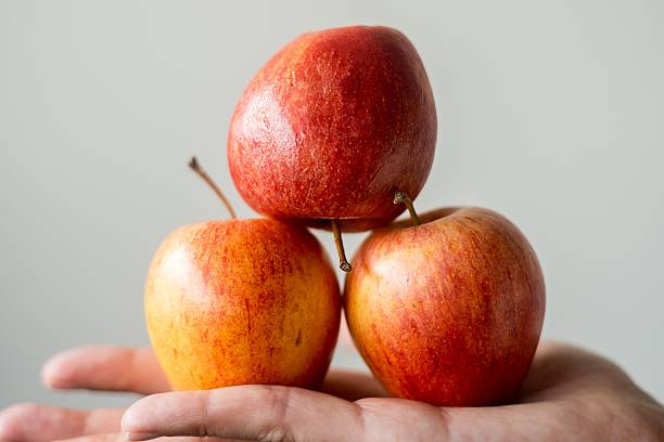 istock Three apples stacked on top of each other in a person's hand 2241276967