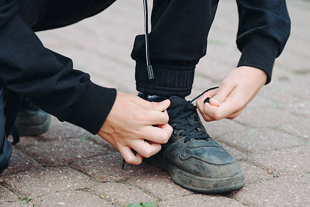 istock young boy ties shoelaces on his foot 2241278520