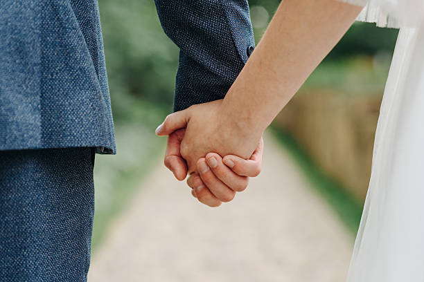istock bride and groom hold hands together 2241278535
