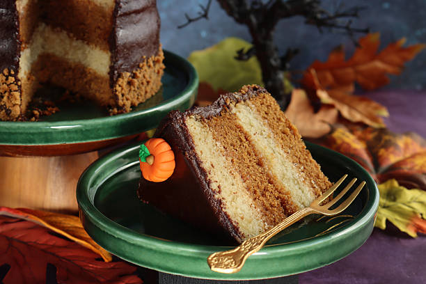 Stock photo shows delicious Halloween cake made with moist chocolate sponge layers, filled with rich caramel icing and topped with smooth cream. Decorated with tiny pumpkins and scattered autumn fall leaves, this dessert captures the essence of cozy seasonal celebrations
