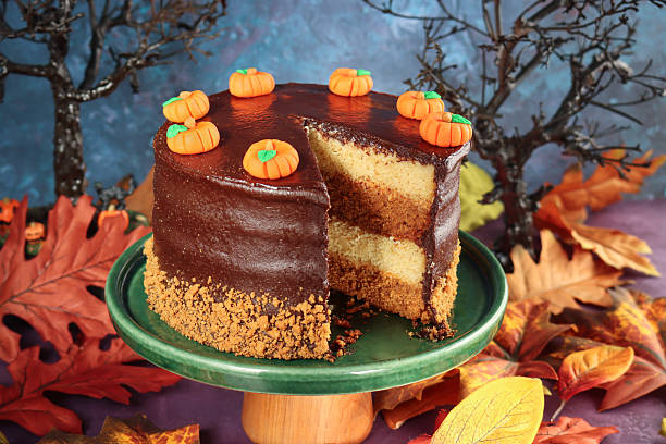 istock Image of halloween chocolate sponge cake with caramel icing and cream, decorated with mini pumpkins and autumn leaves 2241283088